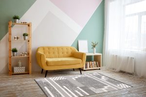 Nice living room with couch, carpet, green plant on a bookcase.