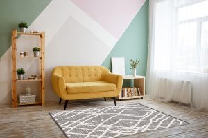 Nice living room with couch, carpet, green plant on a bookcase.