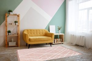 Nice living room with couch, carpet, green plant on a bookcase.