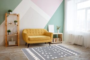 Nice living room with couch, carpet, green plant on a bookcase.
