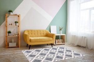 Nice living room with couch, carpet, green plant on a bookcase.